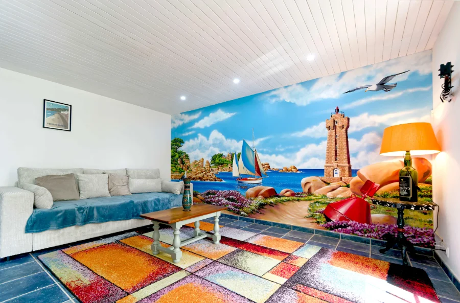Fresque murale en trompe-l'œil dans un salon de particulier : paysage maritime et vieux gréements sur la côte de granit rose, à Ploumanac'h, réalisée par Gwendal Larher